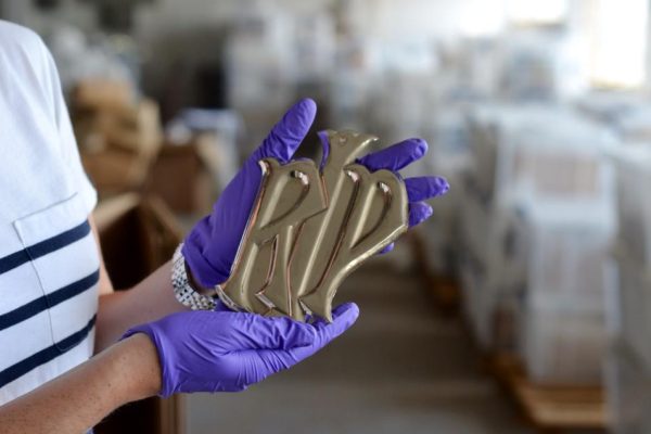 Image of RIP metal plate stamped out being held by museum staff wearing purple gloves.